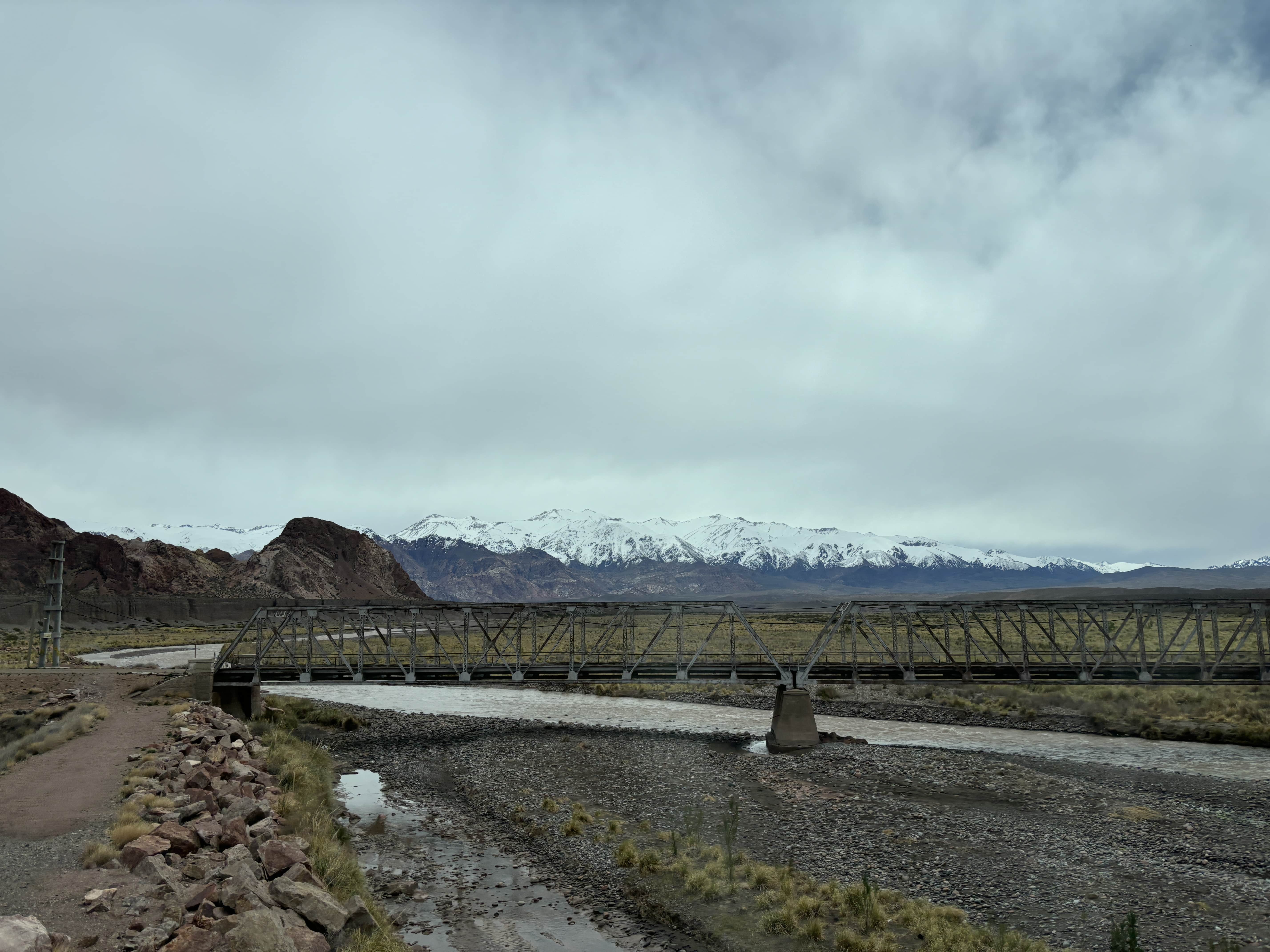 Railway bridge with snow-covered mountains in background.