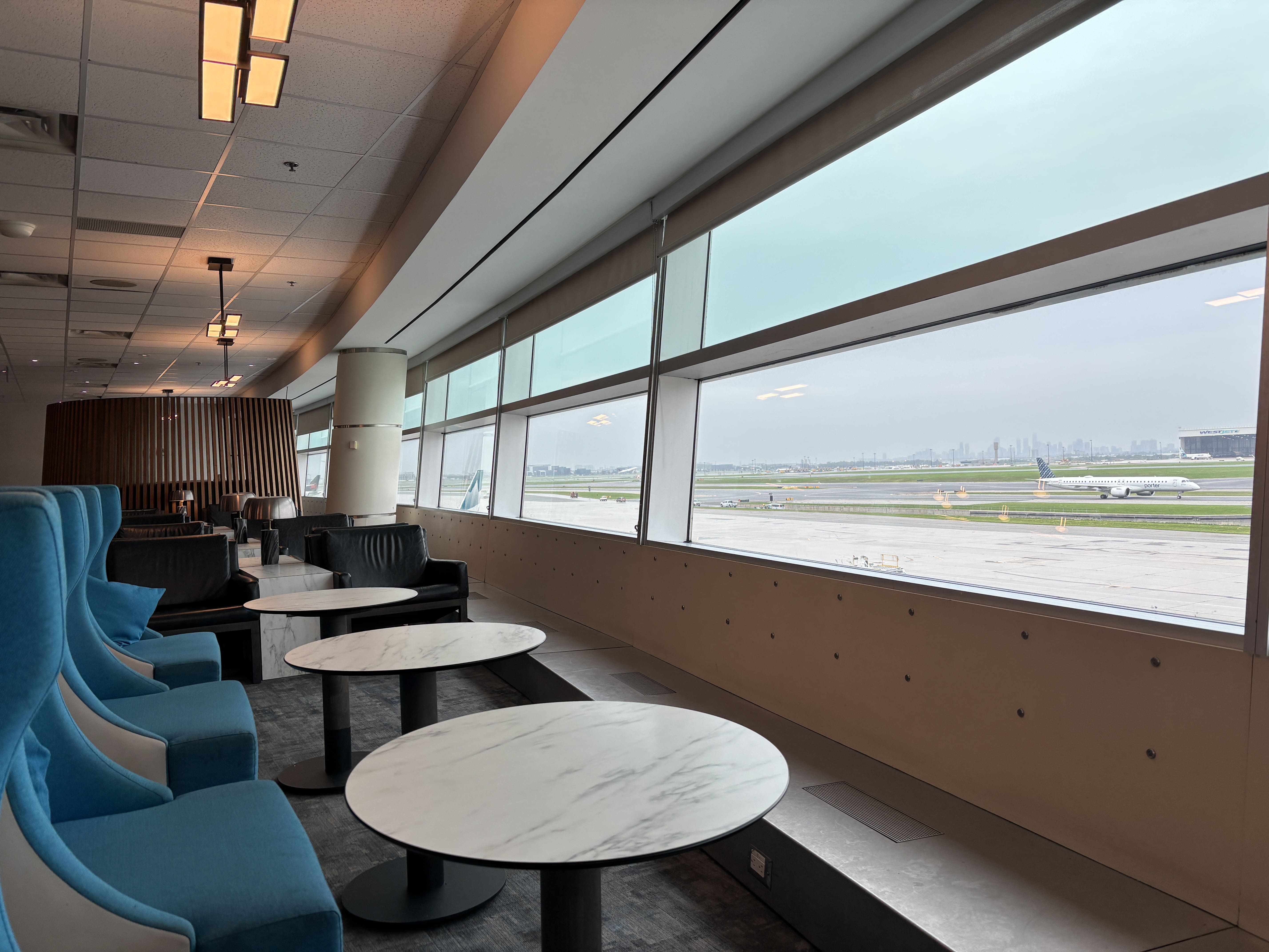 Seating area facing large windows with a view of the apron at Toronto's Pearson International Airport.