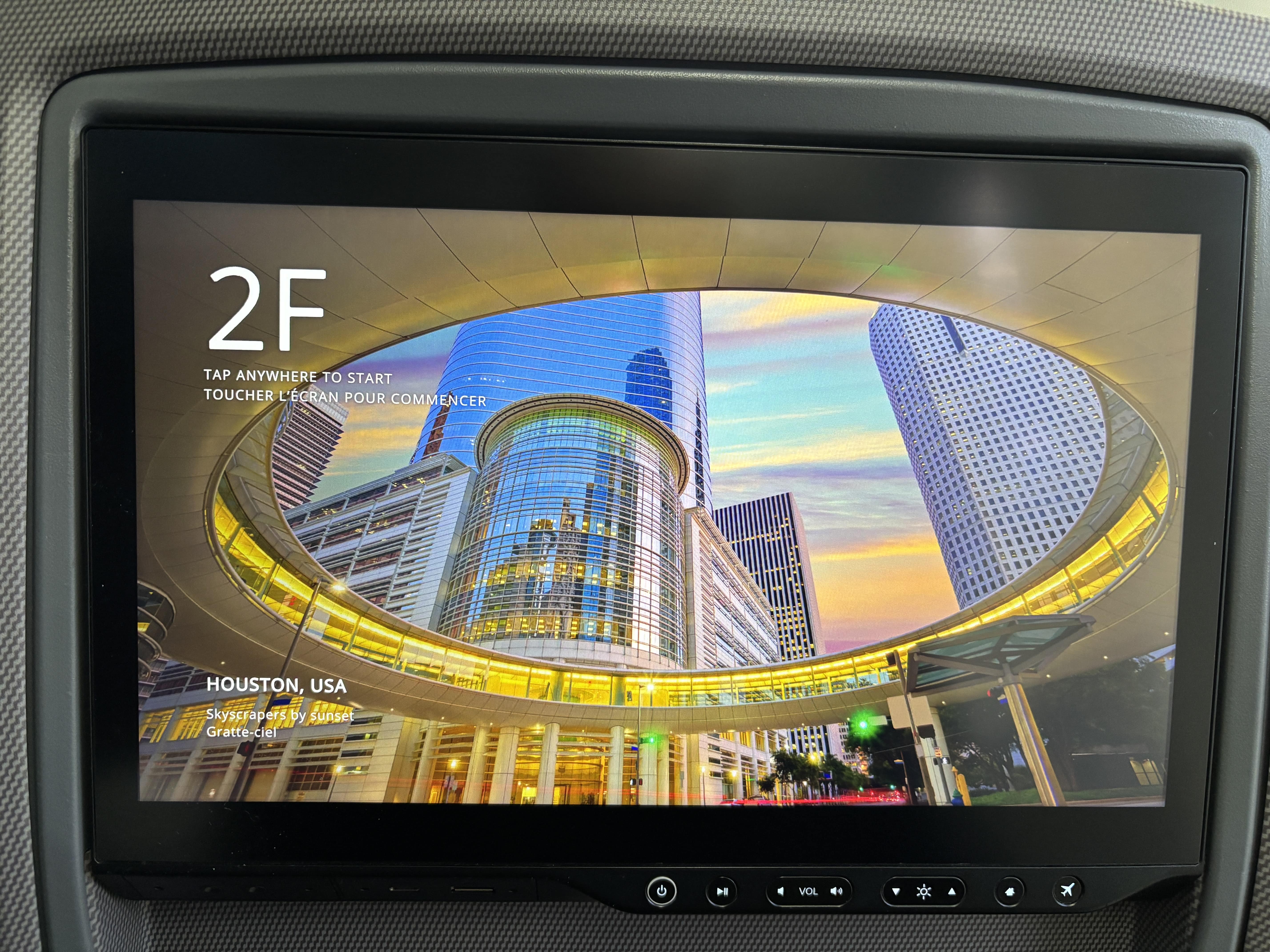 Seat-back in-flight entertainment screen, with buttons at the bottom to control power, volume, brightness, and bring up the menu or flight map.