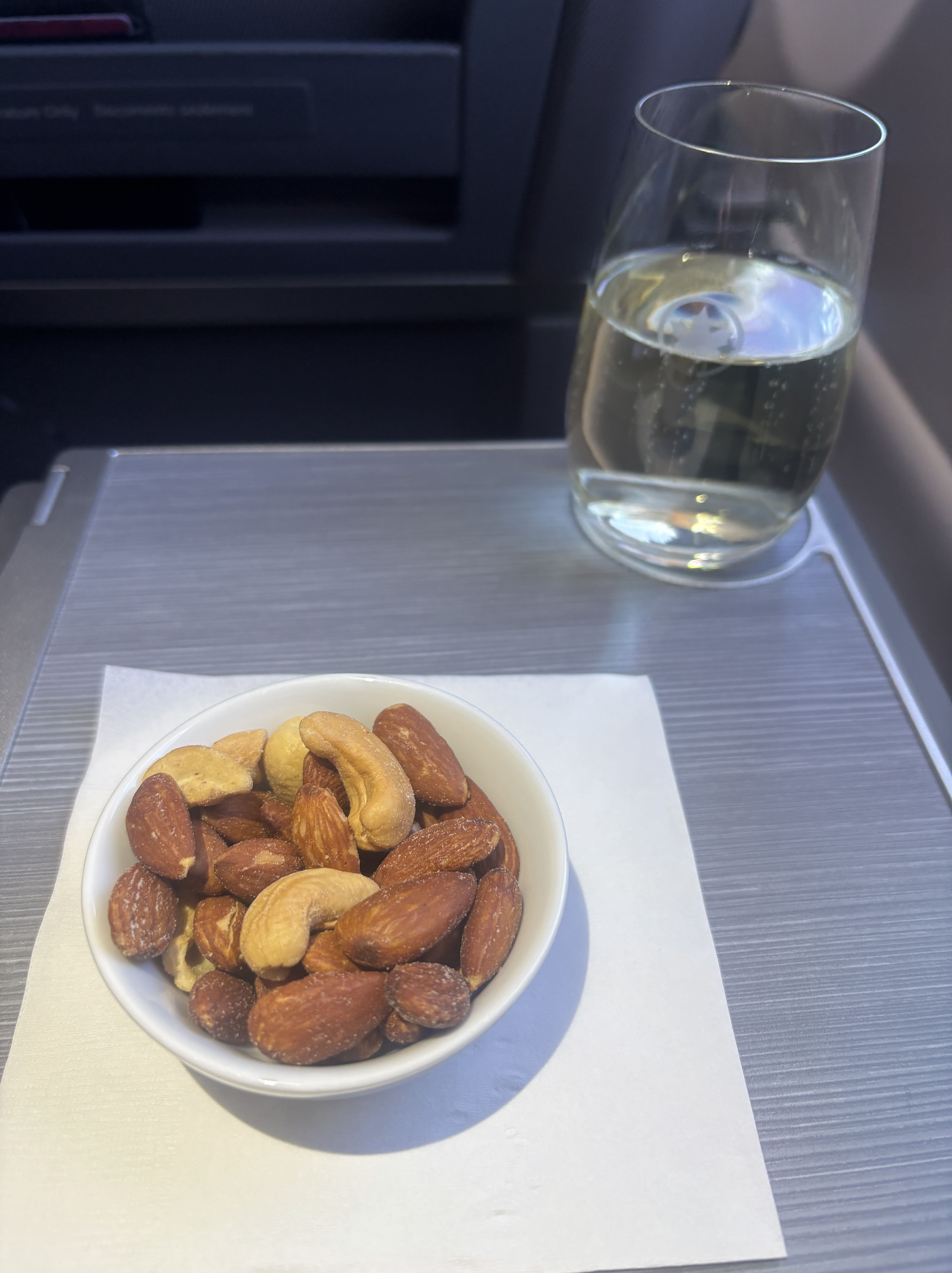 Small tray of mixed nuts and a glass of sparkling wine, with frosted maple leaf logo showing.