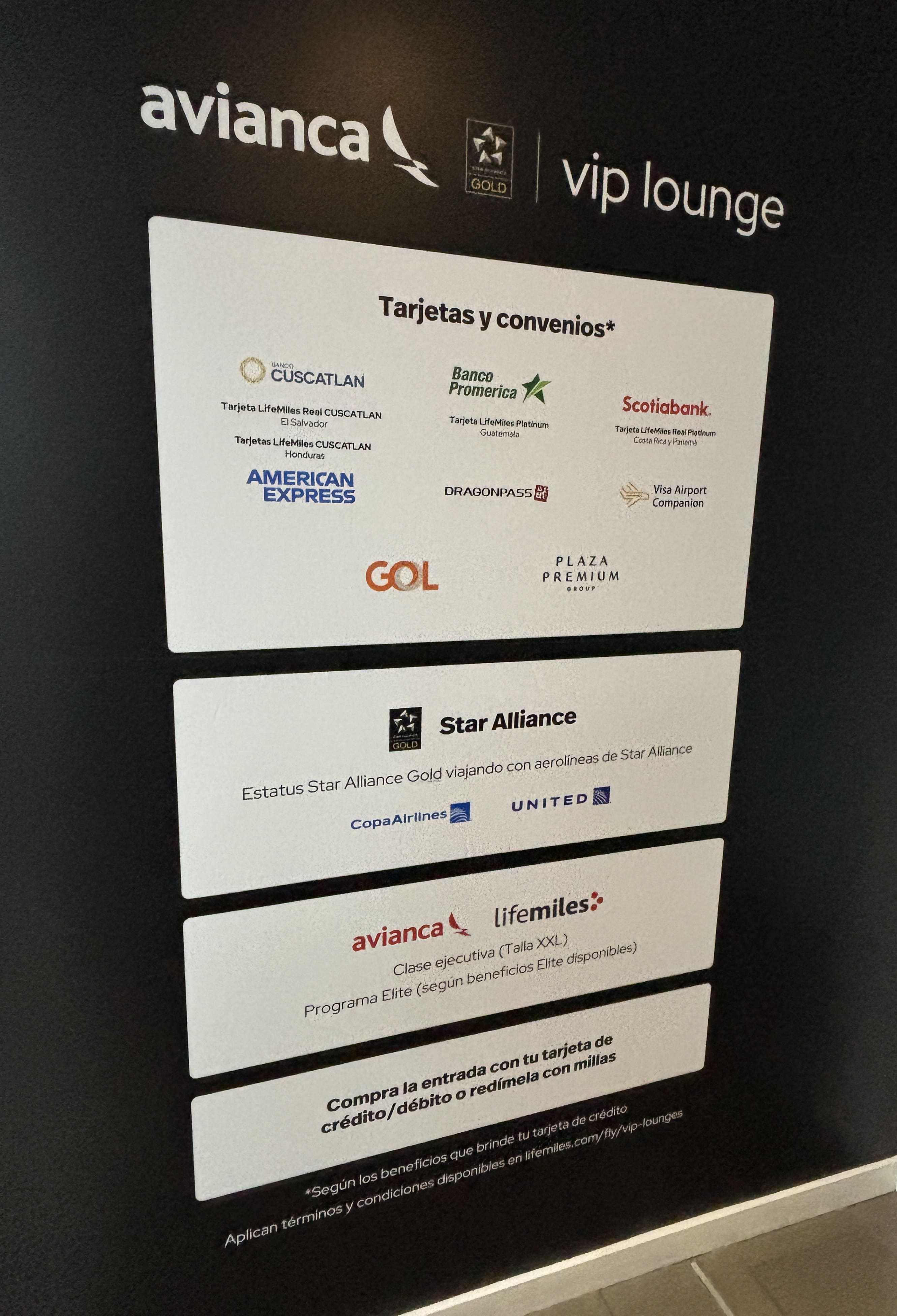 Sign outside the Avianca lounge in San Salvador showing broad entry permissions for credit card and lounge pass holders.
