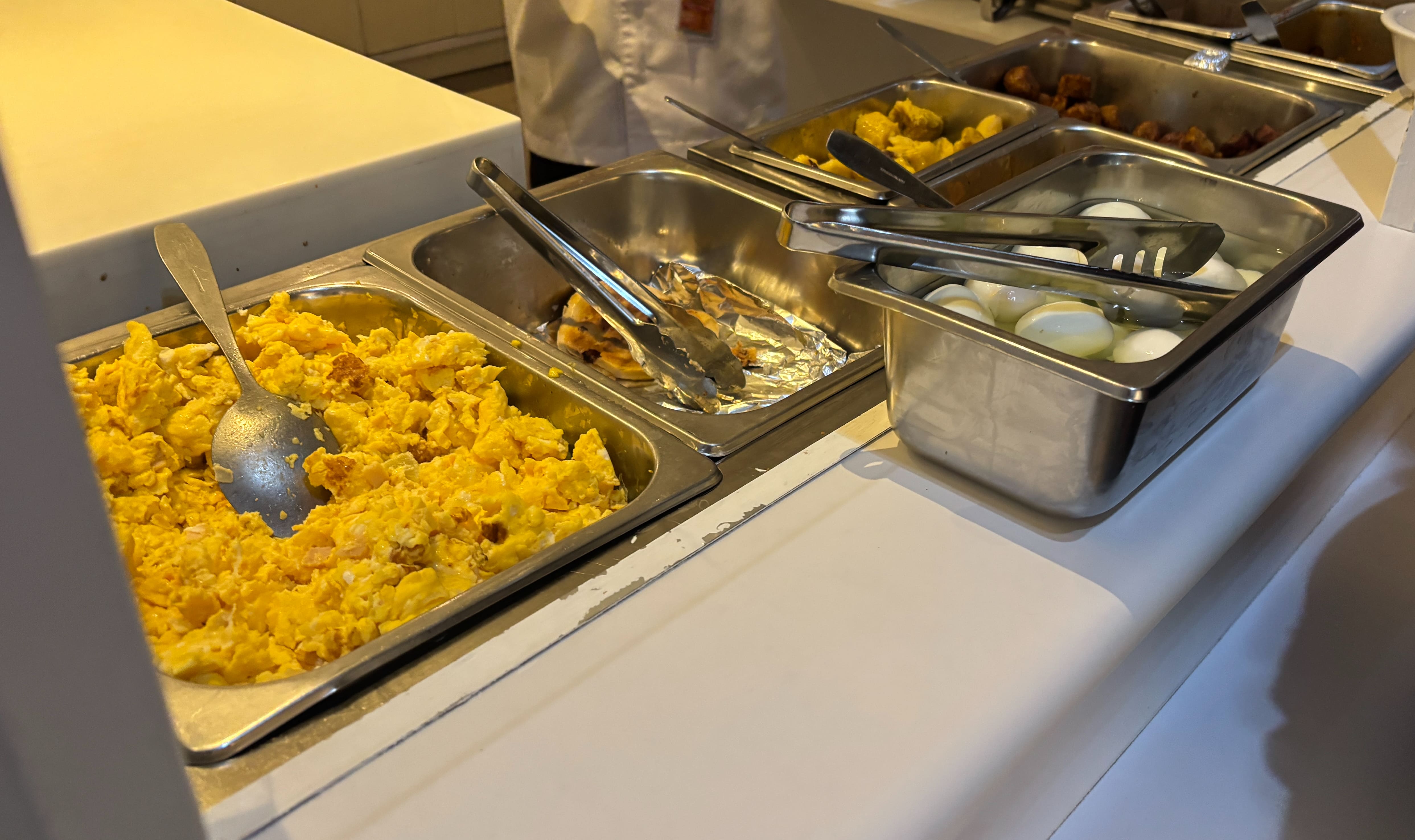 Hot food options at the Avianca lounge in San Salvador: eggs, scrambled and hard boiled, as well as pancakes, plantains, and potatoes.