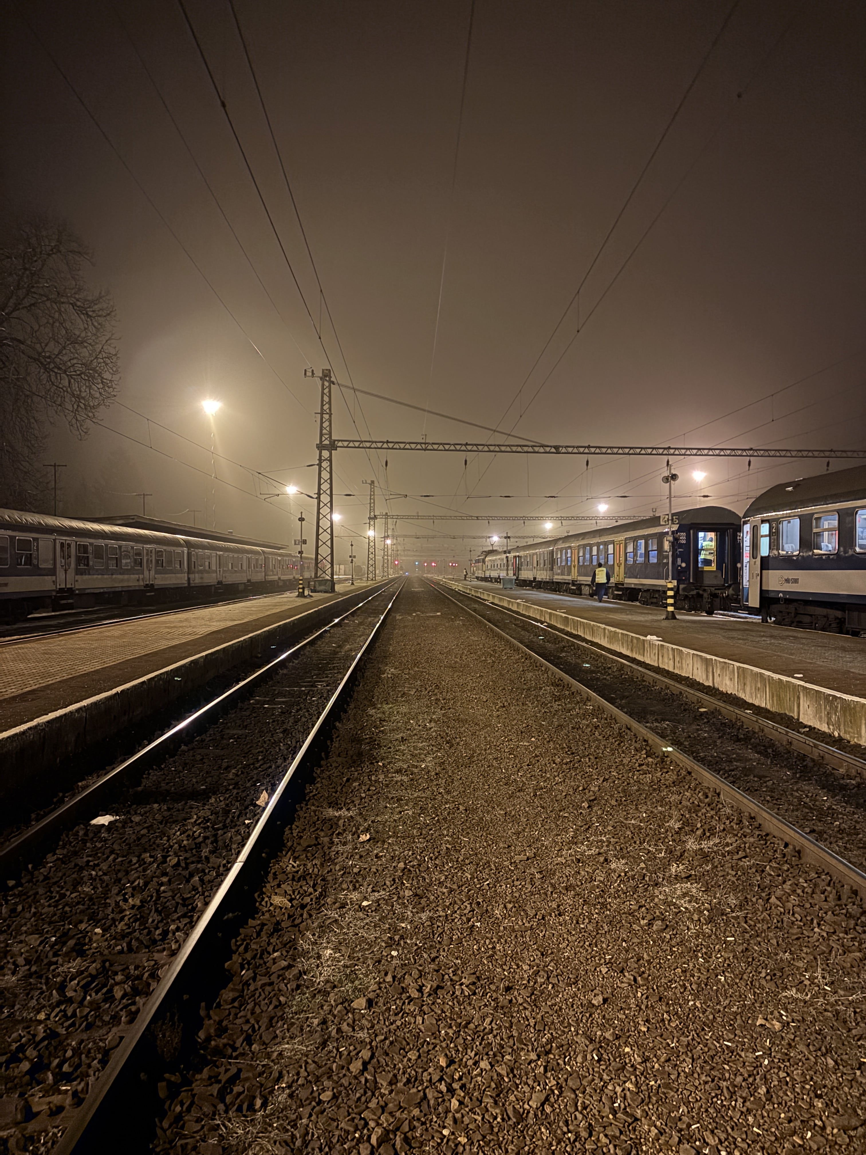 Standing between tracks with fog obstructing a dark sky.