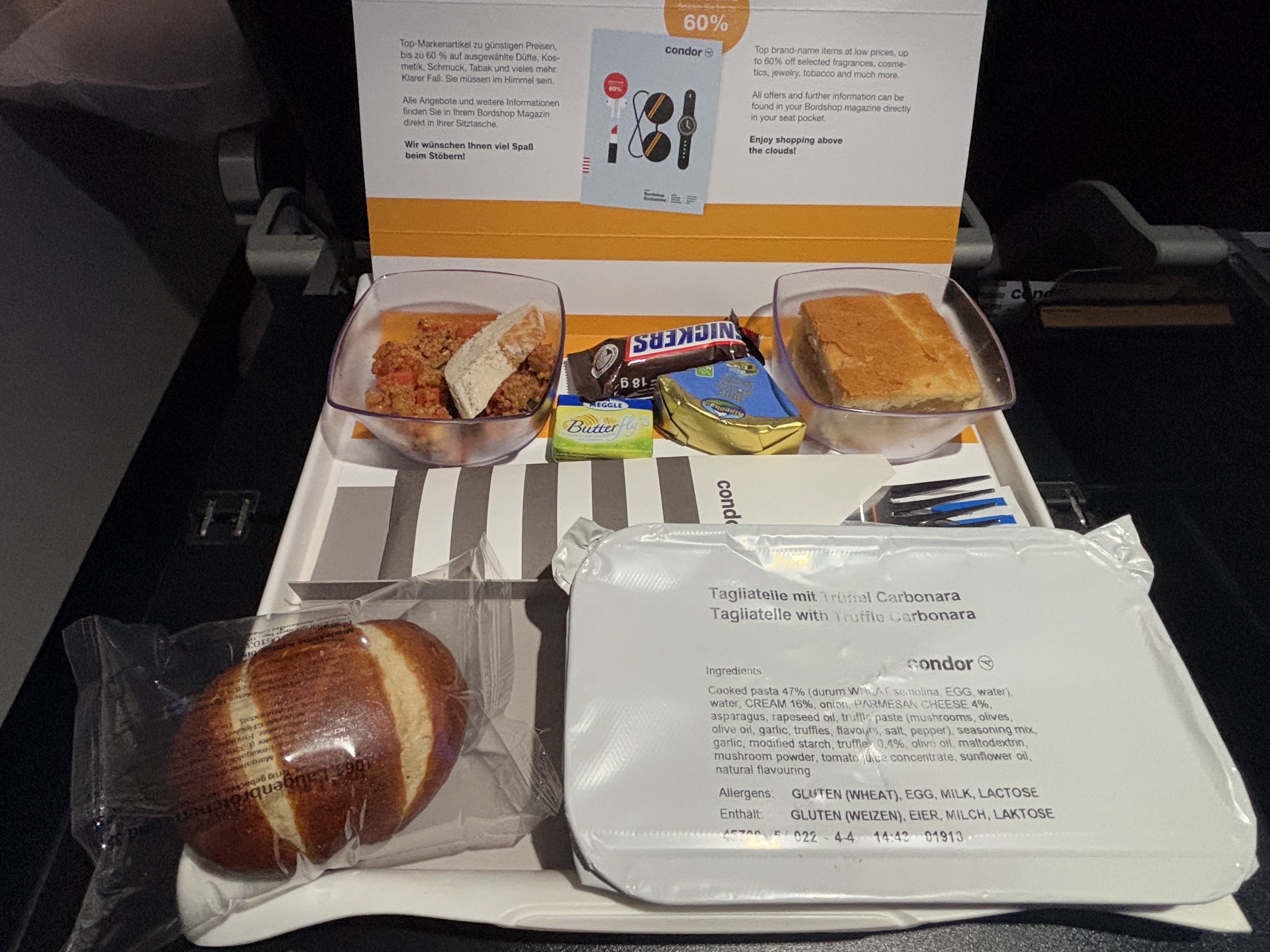 Single-tray meal service with food still in plastic packaging.