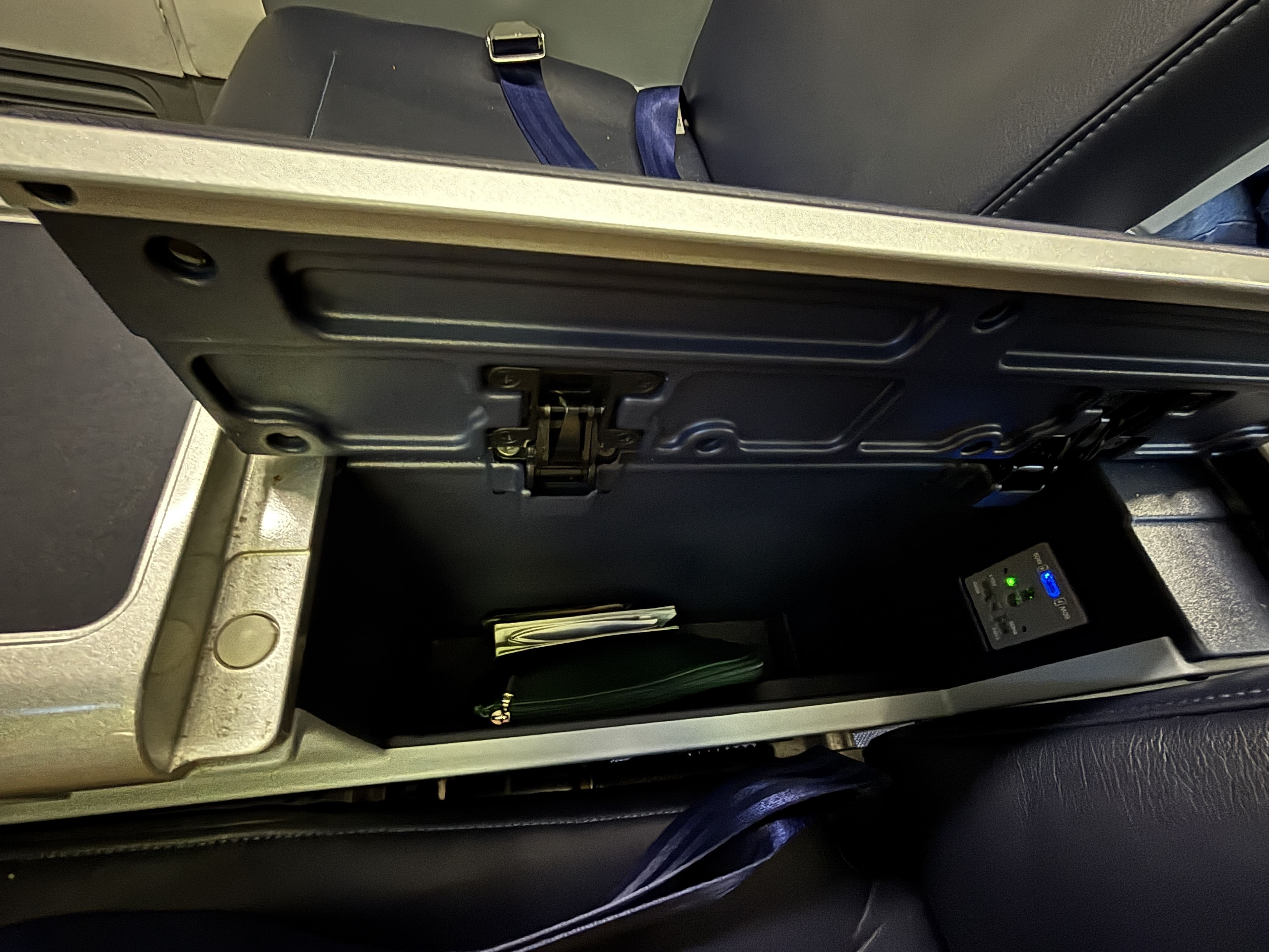 Small storage cubby next to each seat, with universal plug and USB-C charging point.
