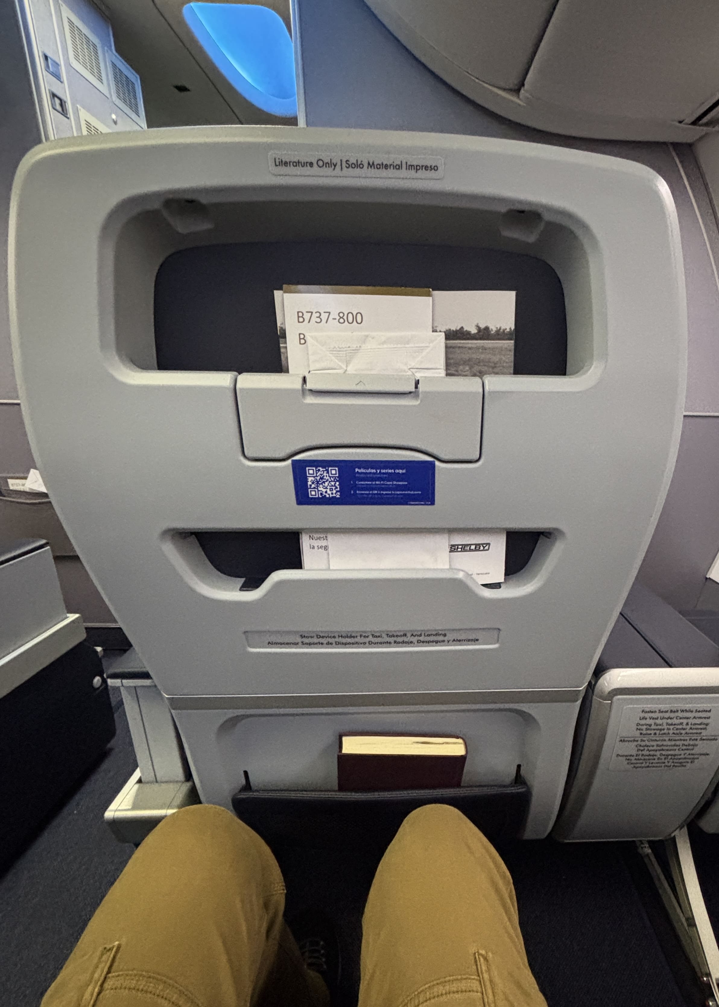 Seatback showing fold-down device holder and QR code to scan for WiFi access.