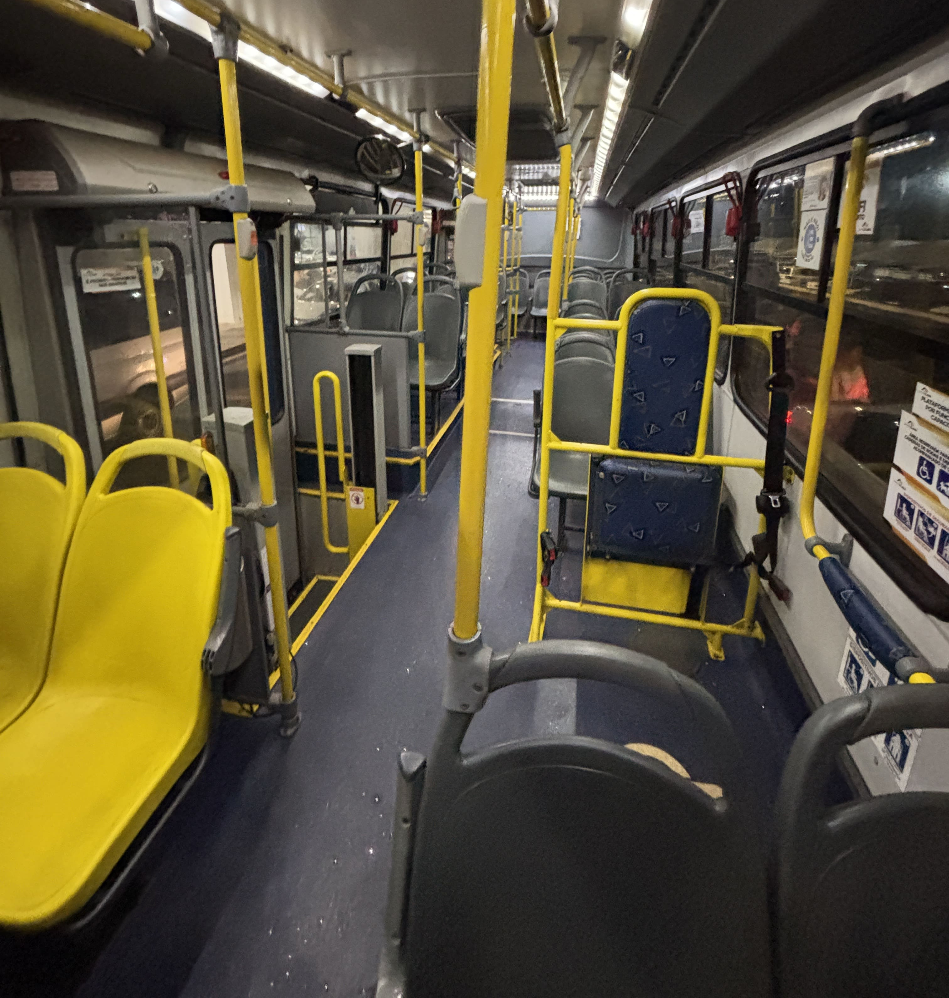 Interior of a local bus in Foz do Iguaçu,showing empty blue and yellow seats.