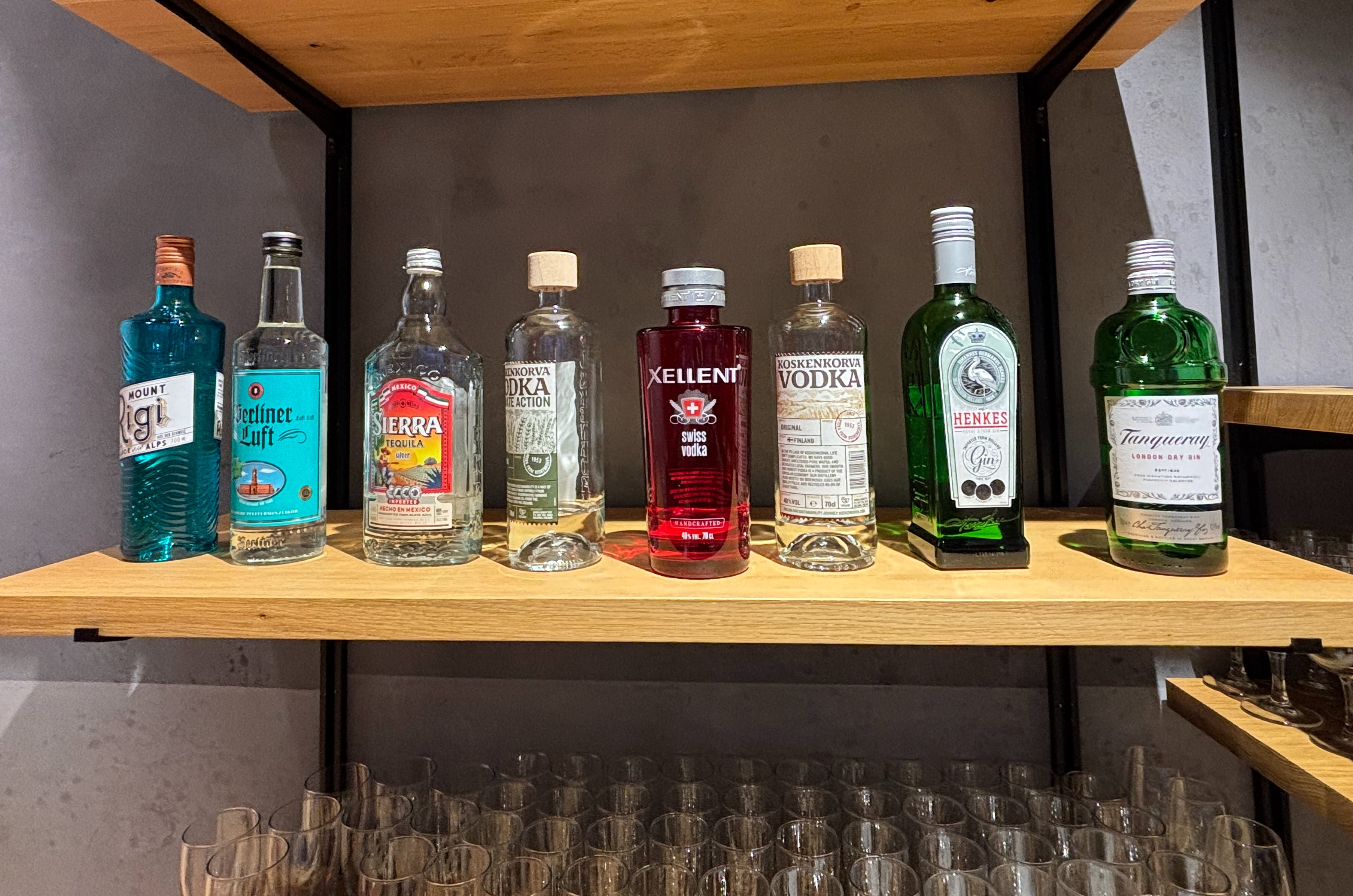 Bottles of clear spirits arranged on a wooden shelf.