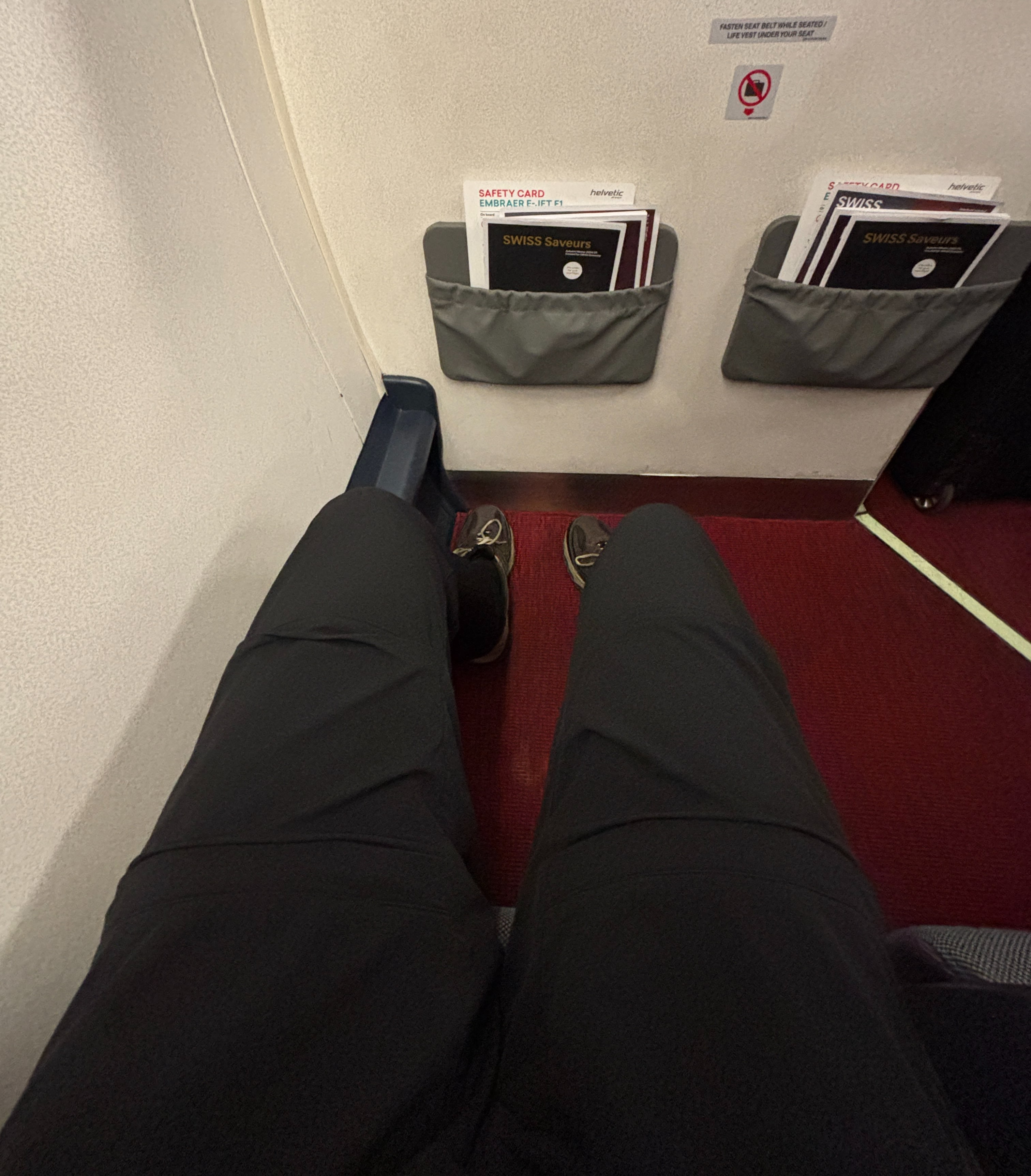 Outstretched legs in the front row of an Helvetic Airways E195.