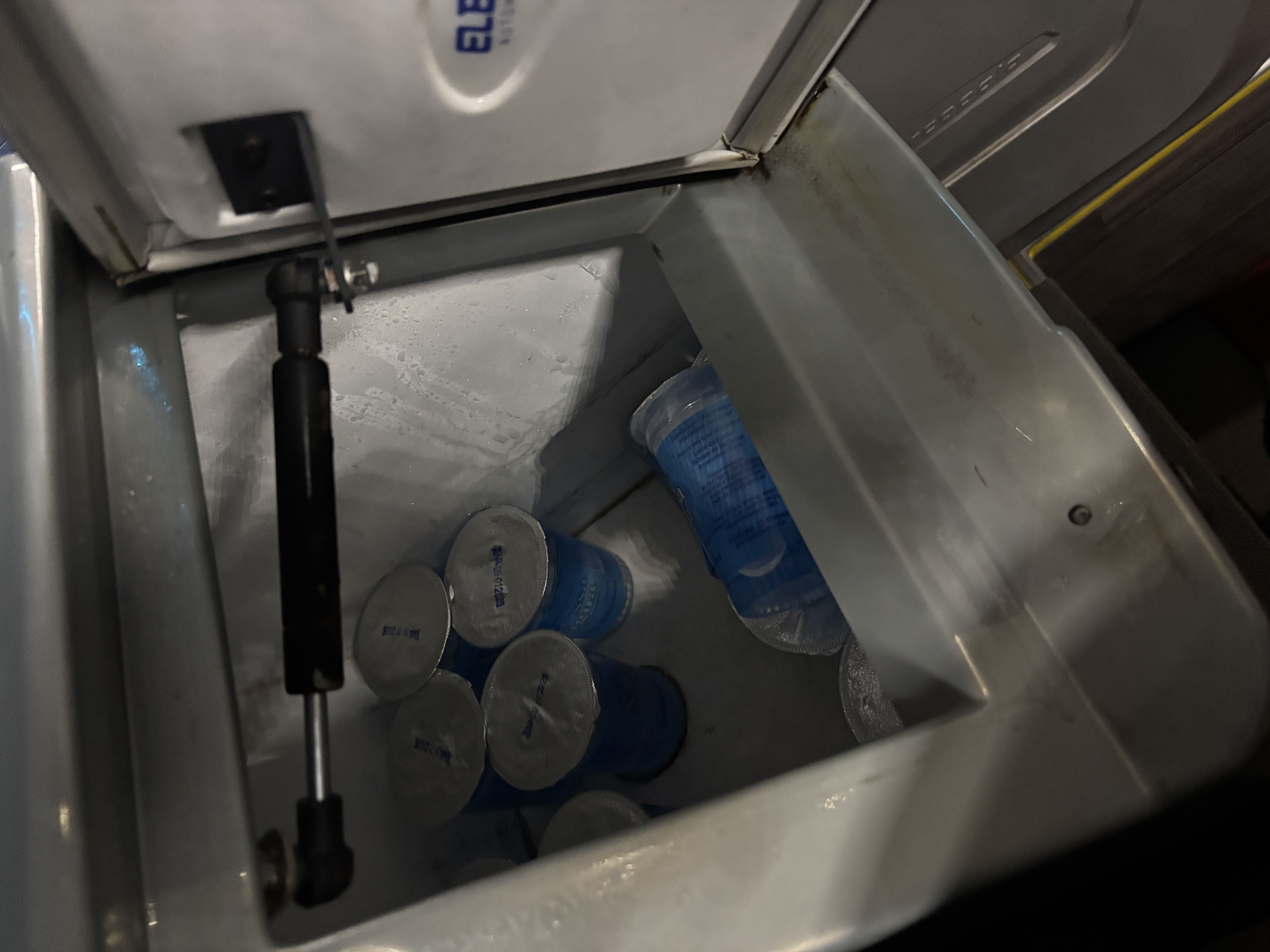 Open cooler showing small, sealed plastic cups of water.