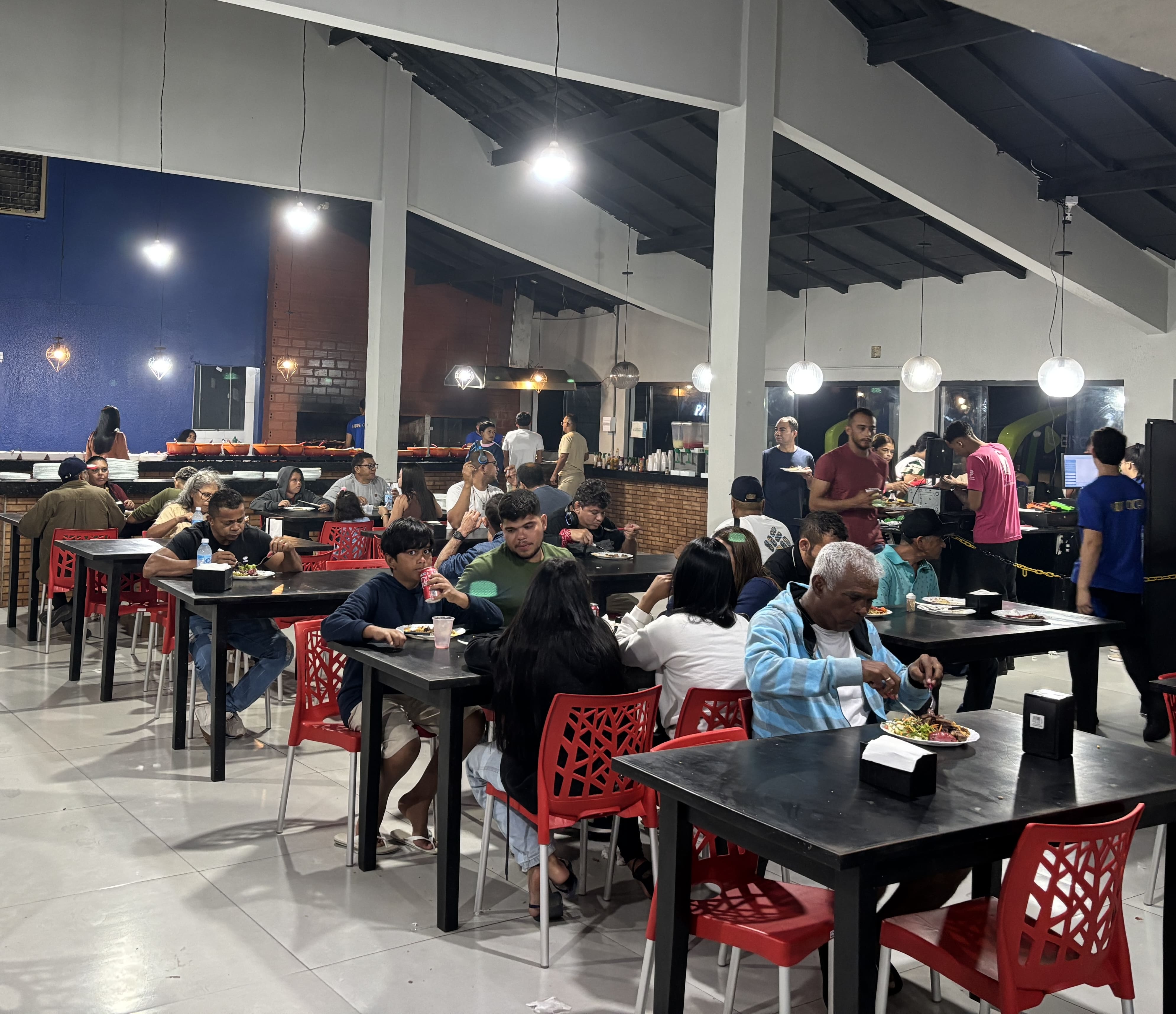 Interior of Restaurante Padre Cicero showing tables, chairs, and a buffet line.