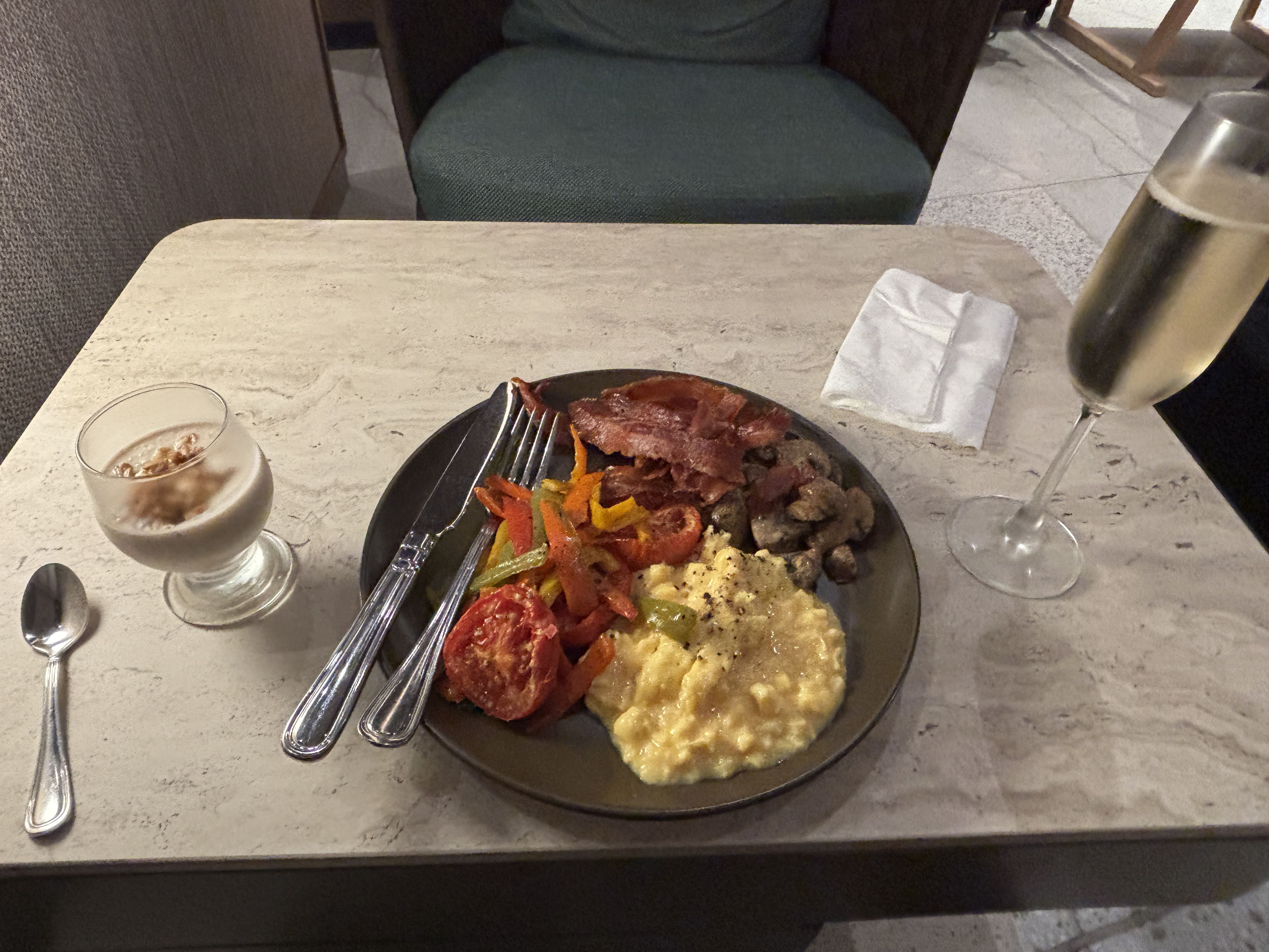 Breakfast service at the LATAM Premium Lounge in Lima: overnight oats, sautéed vegetables, bacon, scrambled eggs, and a flute of sparkling wine.