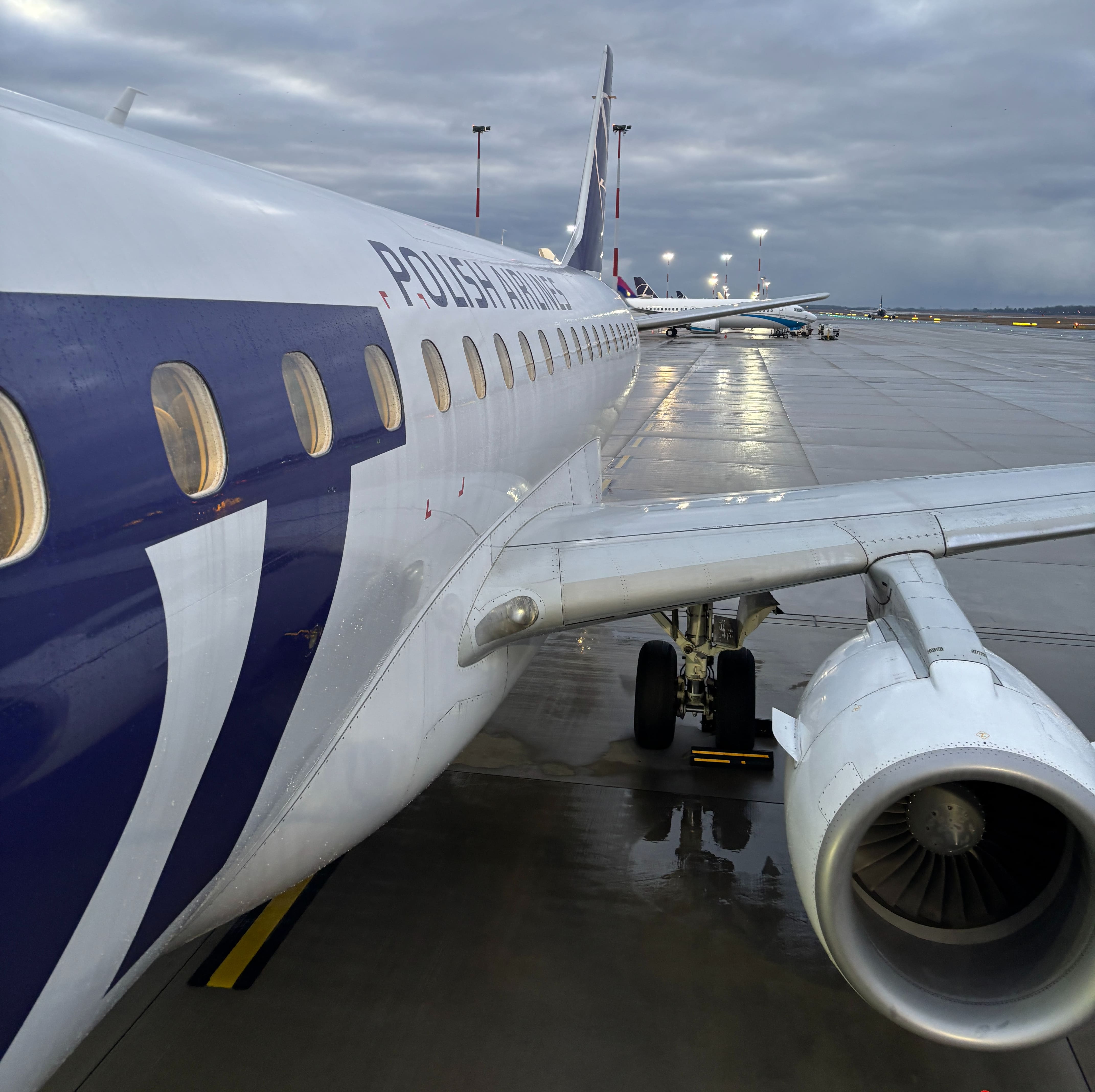 LOT Polish Airlines aircraft seen after stepping out the front left exit, with white fuselage and blue lettering.