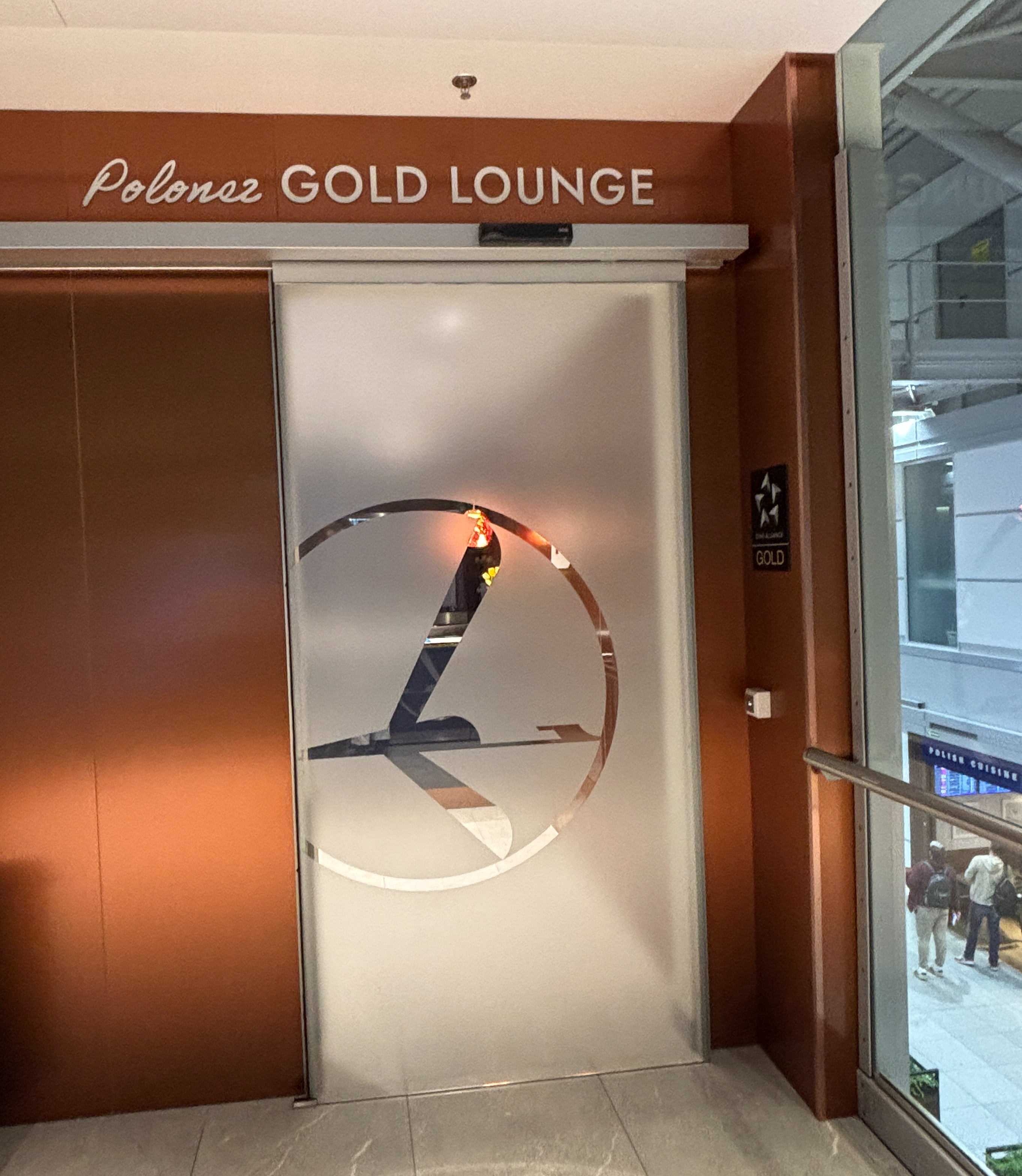 Frosted glass sliding door beneath sign for the Polonez Gold Lounge, with Star Alliance Gold sign hanging beside the door denoting entrance eligibility.