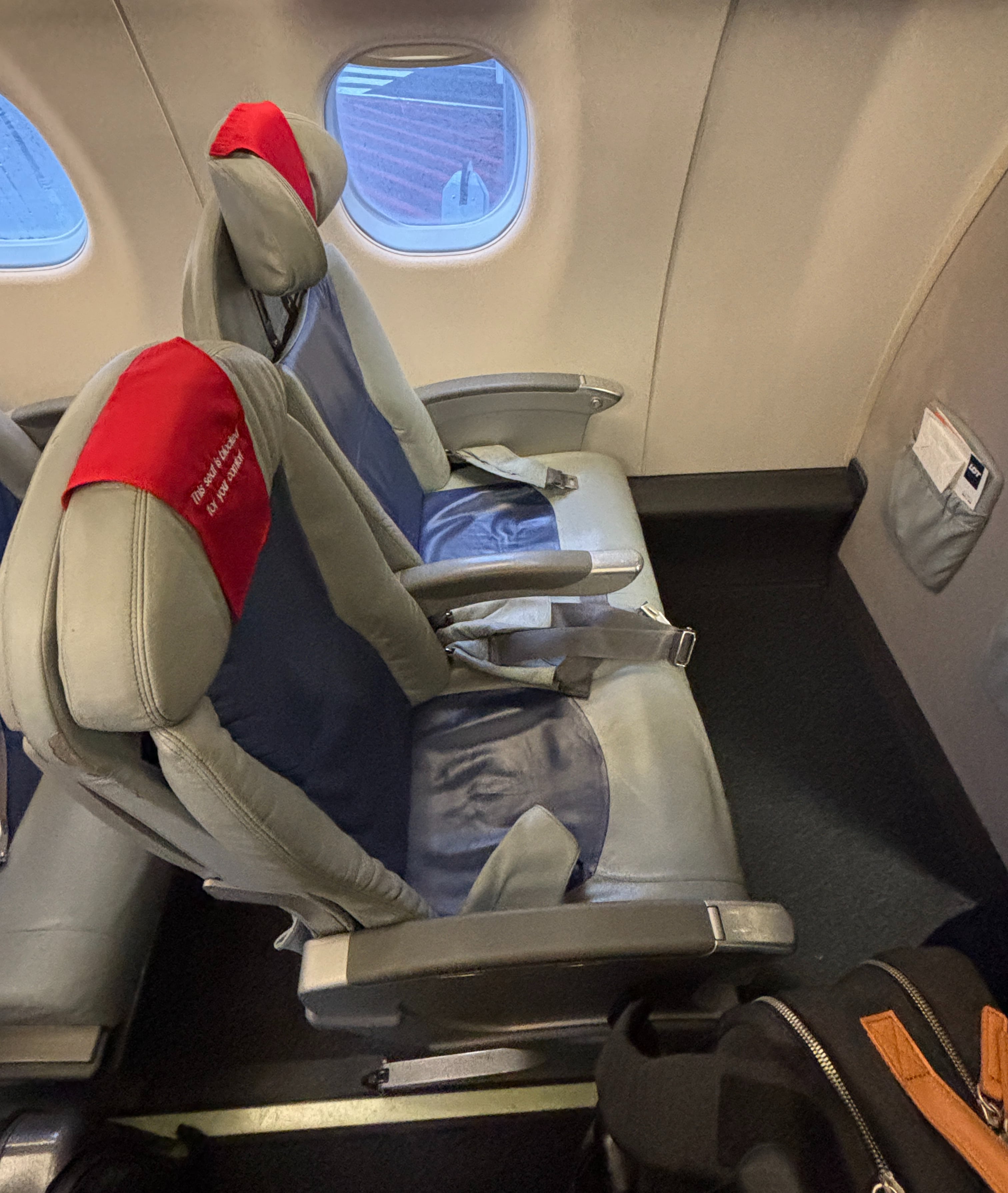 Pair of beige and blue padded seats in front row with same text as above.