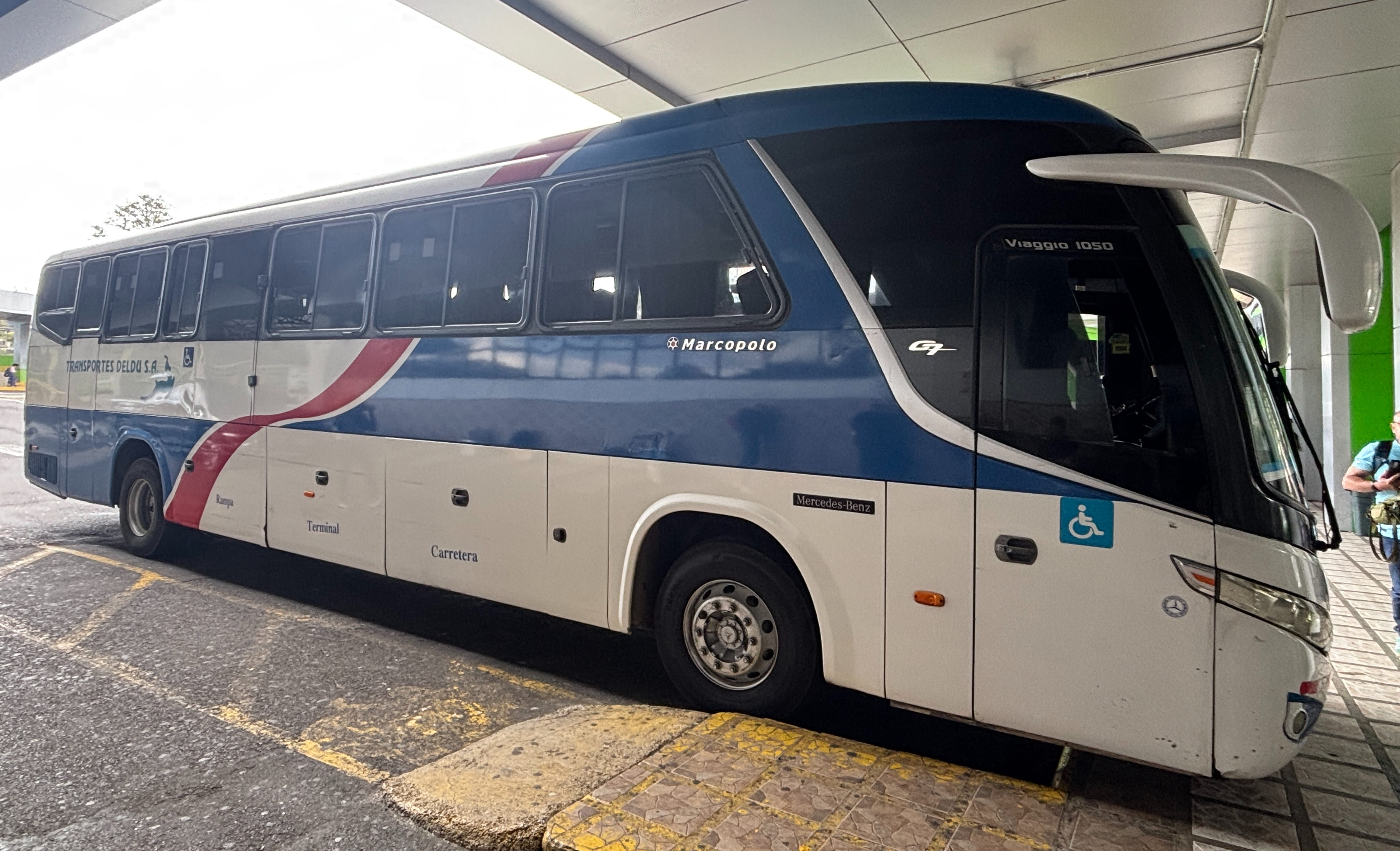 White, blue, and red bus of Transportes Deldu waiting at the bus terminal in San José, Costa Rica.