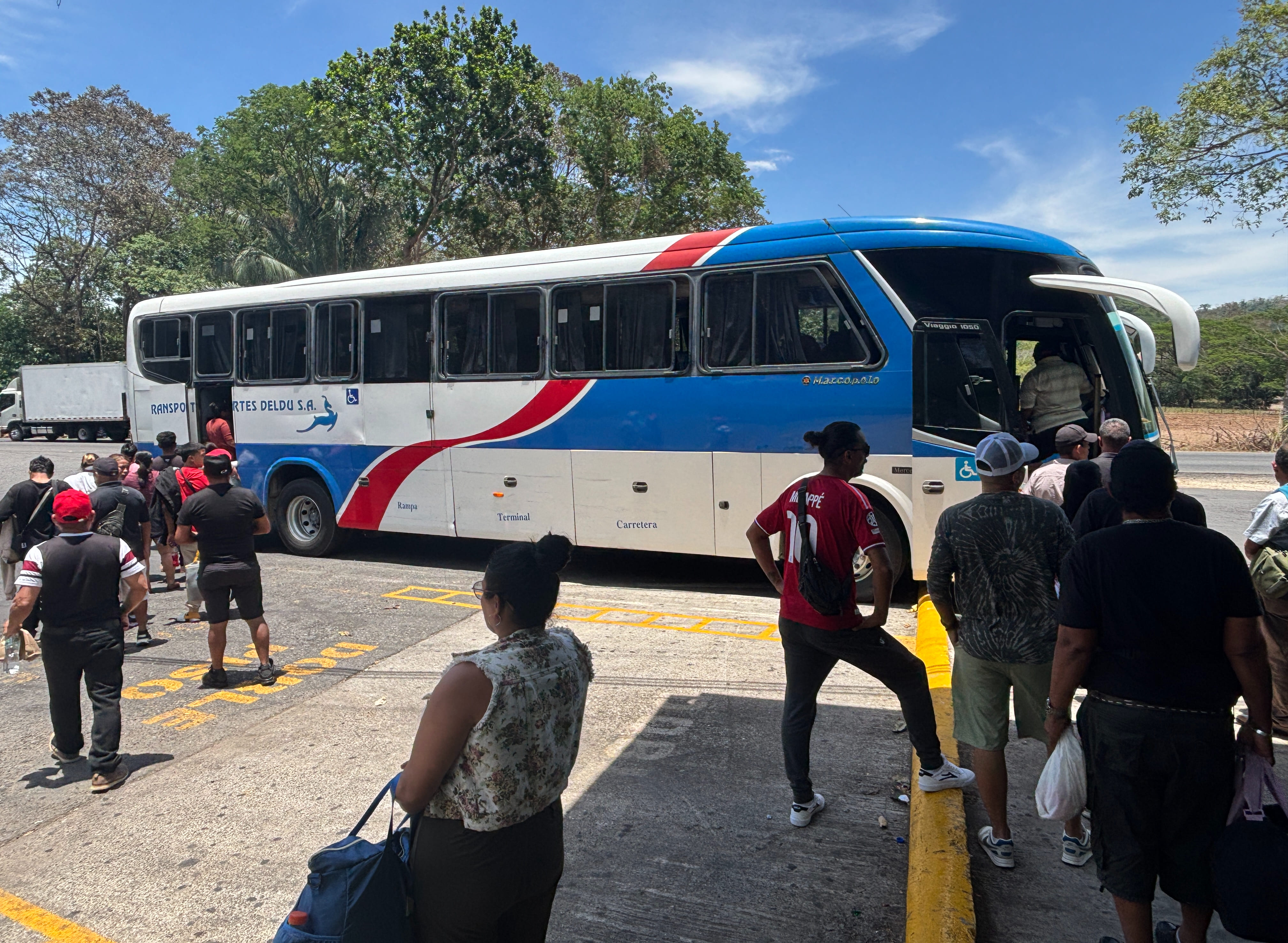 Passengers waiting to board a Transportes Deldu bus after a brief mid-journey lunch break.