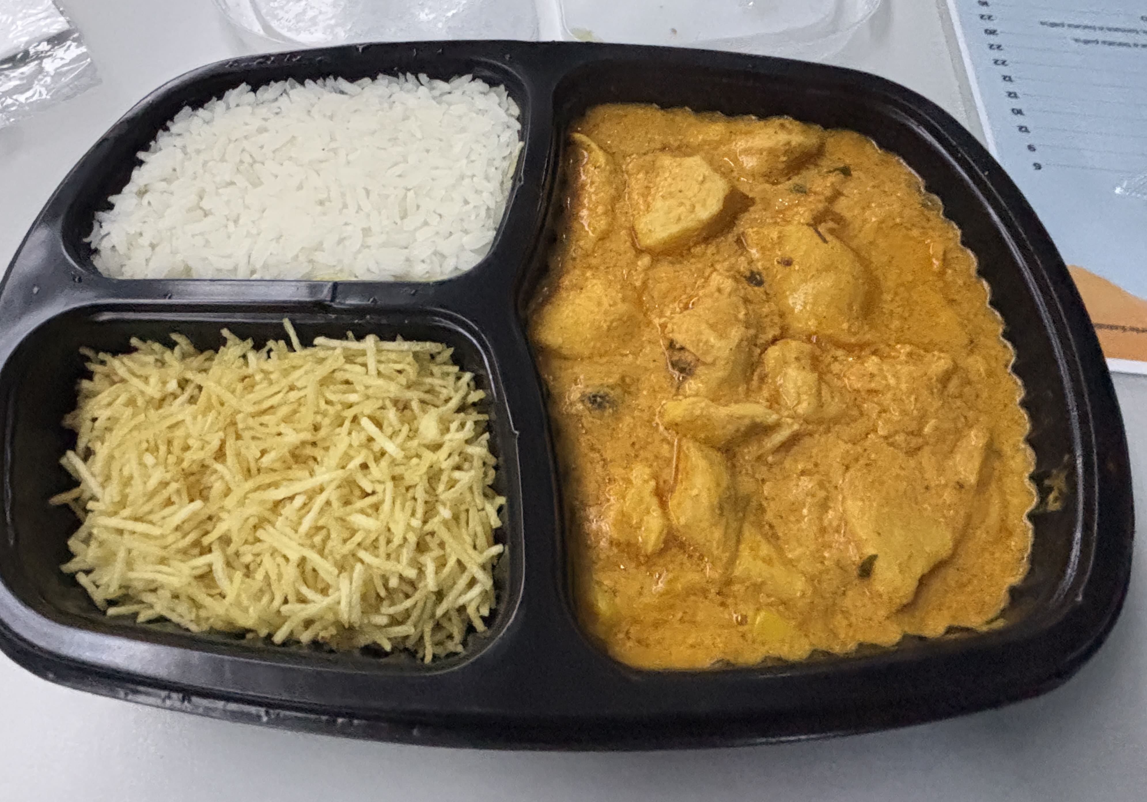 Chicken stroganoff, plain white rice, and *batata palha* in a black plastic tray.