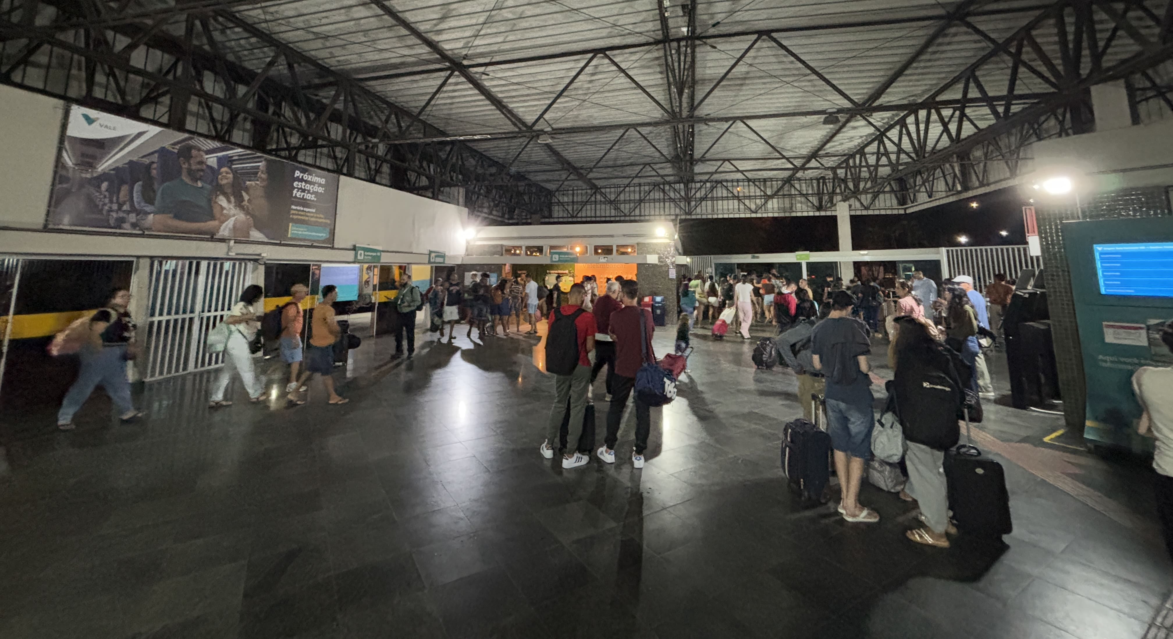 Pedro Nolasco station, dimly-lit, showing a stream of passengers disembarking the train.