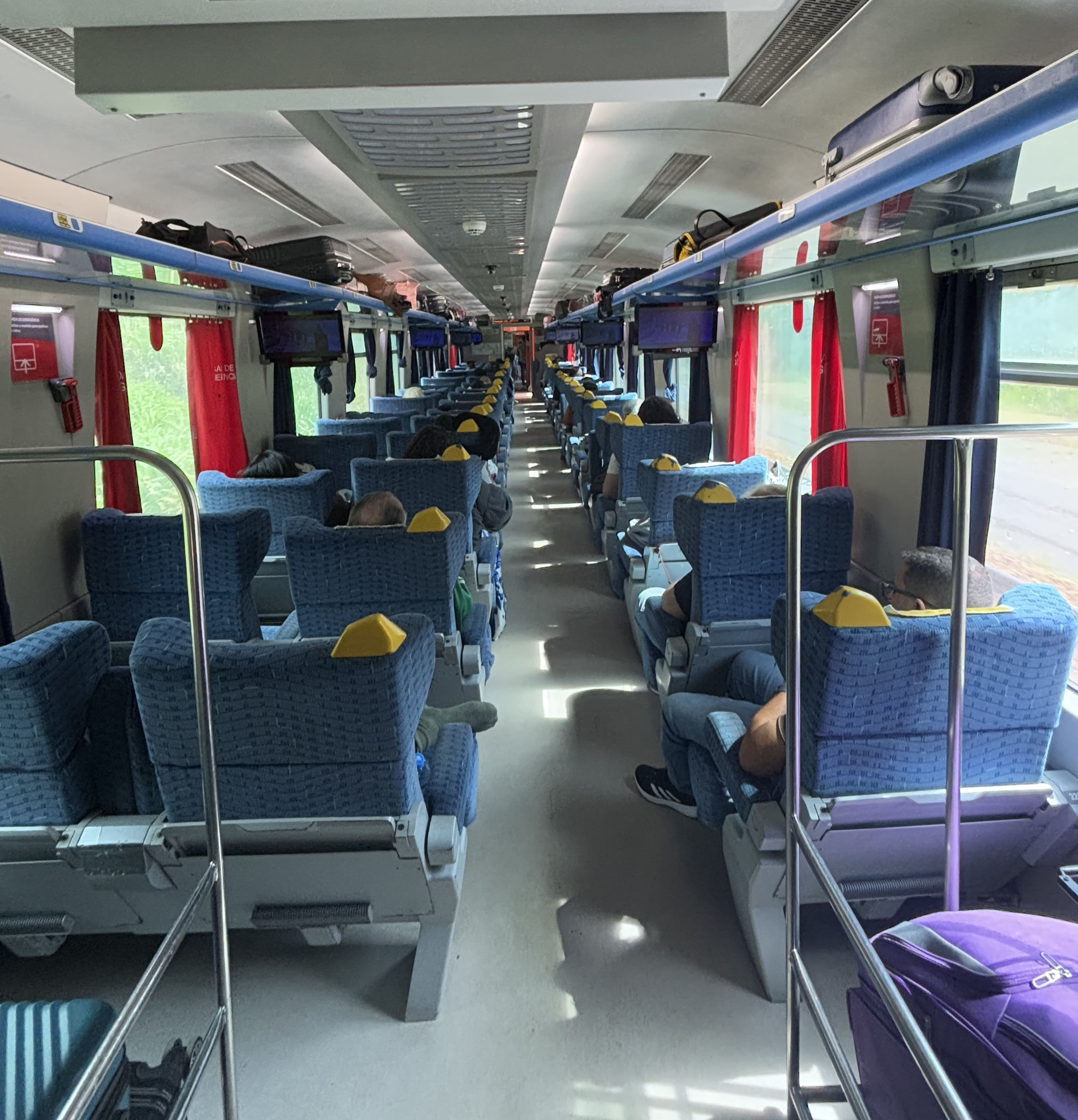 Interior of an executive class carriage, showing seating arranged 2-1 with luggage storage overhead.