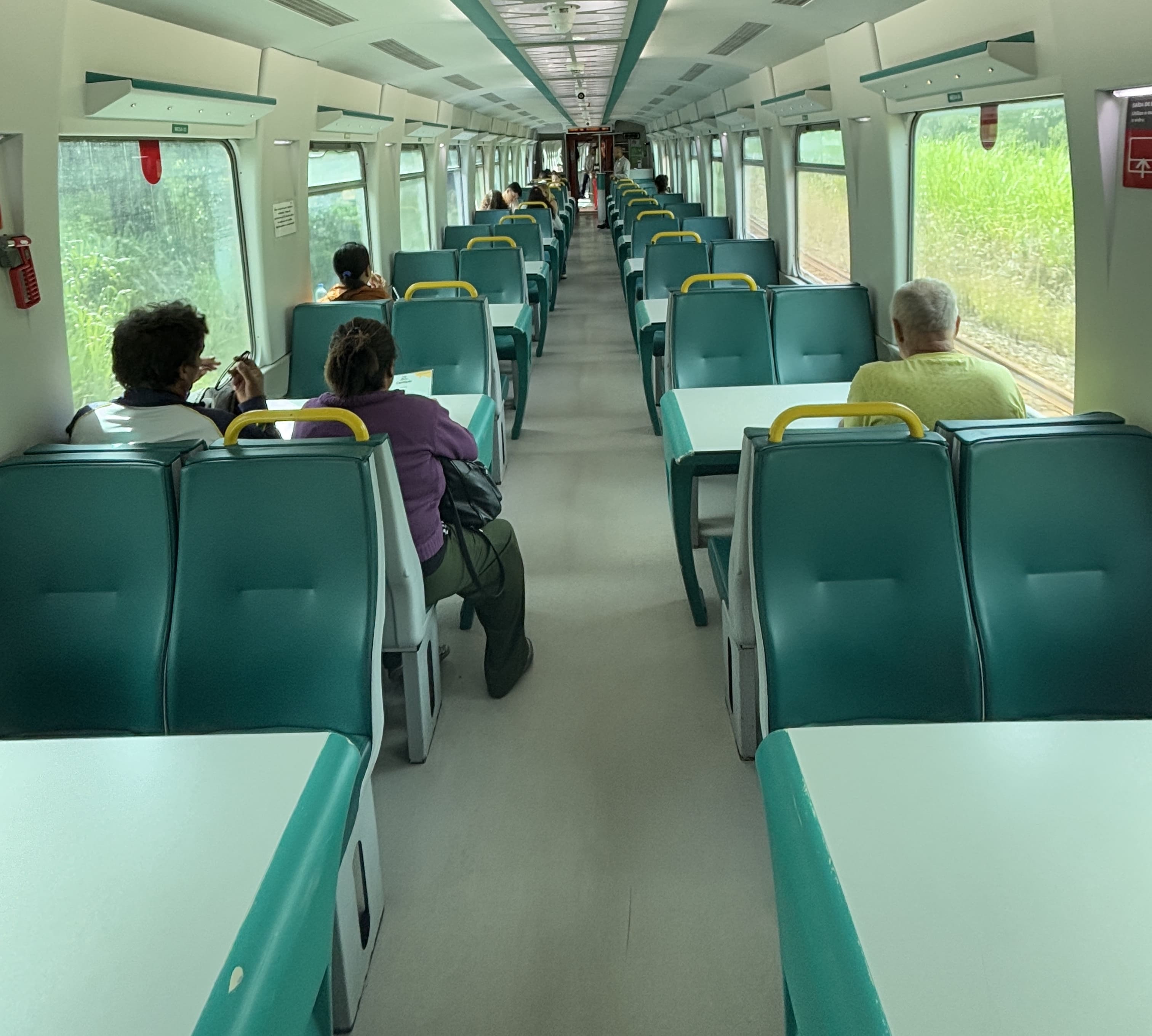 Dining car aboard the Vale passenger train, showing green plastic seats arranged in groups of four around a table.