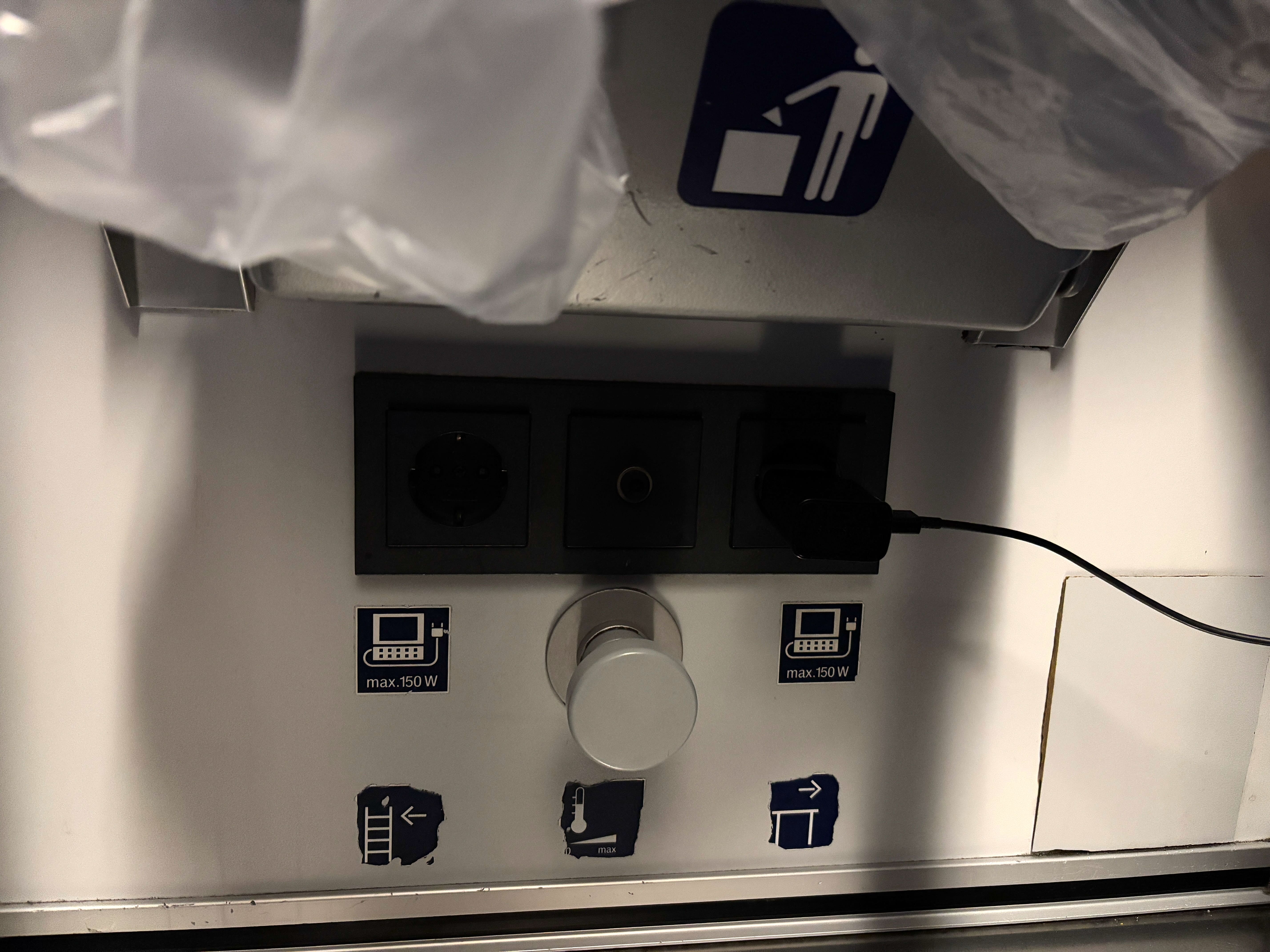 Two European-style power sockets located underneath a small metal trash bin.