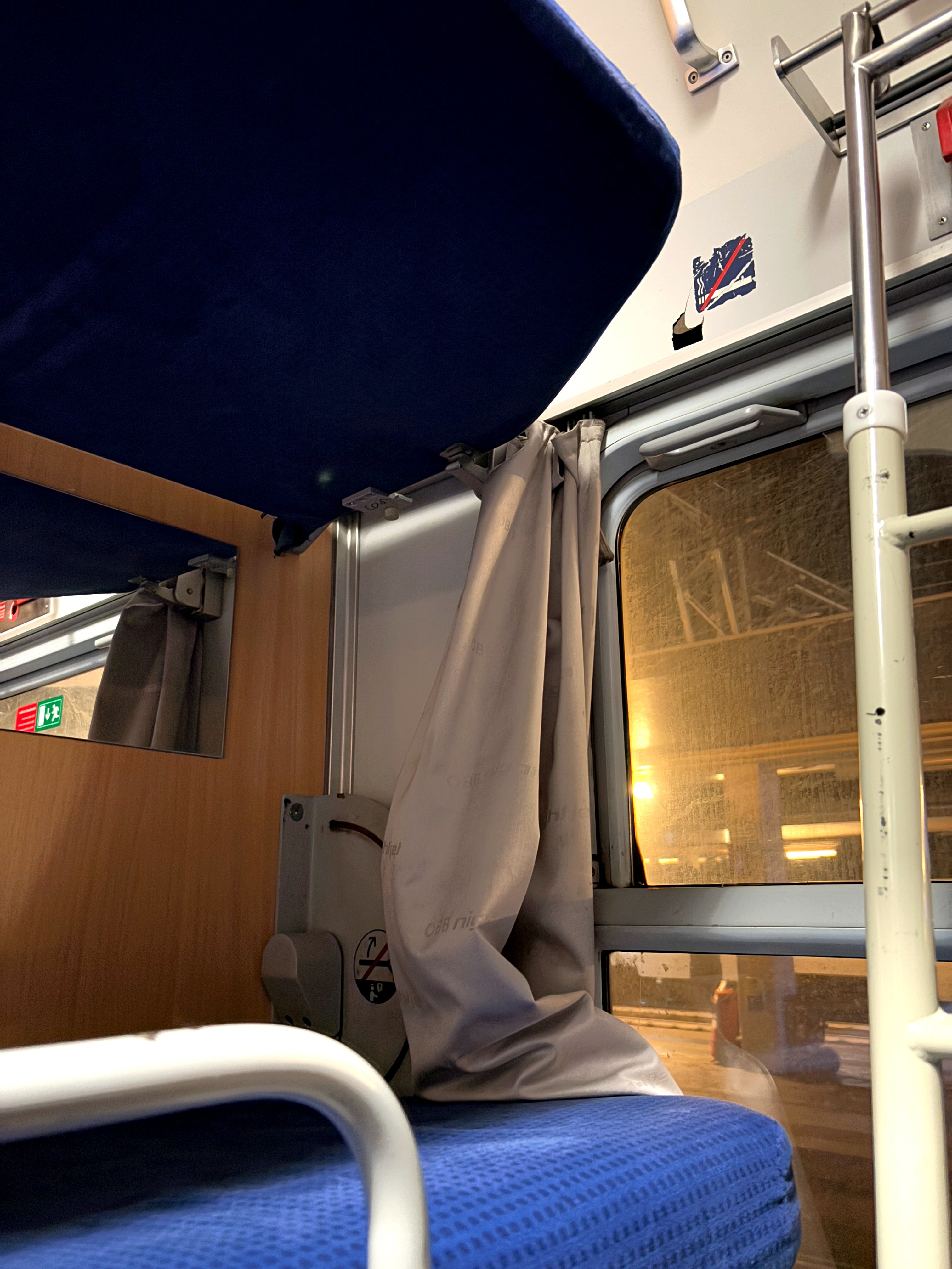 Small beige curtain resting on the middle bunk, drawn open.